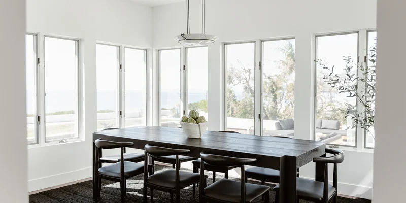Minimalist dining room with large windows and ocean views.