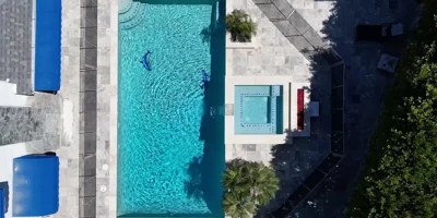 Aerial view of a fenced pool and hot tub surrounded by greenery.