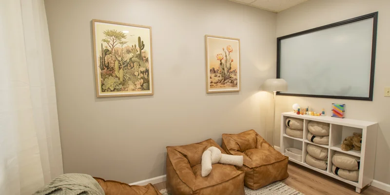 A therapy room with bean bag chairs, soft lighting, and decor.
