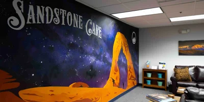 A waiting area with a mural reading "Sandstone Care" and a leather couch.