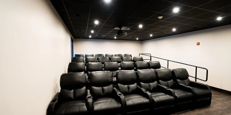 Private theater with black reclining seats and projector.