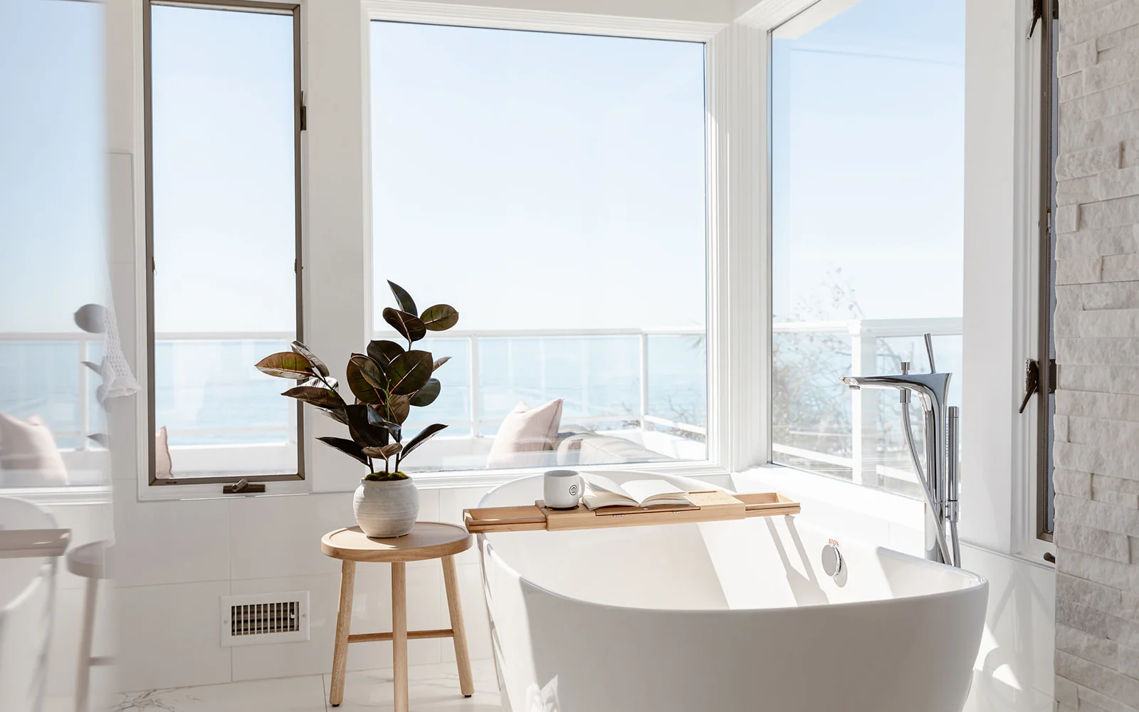 Bright bathroom with a freestanding tub and ocean views.