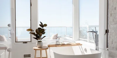 Bright bathroom with a freestanding tub and ocean views.