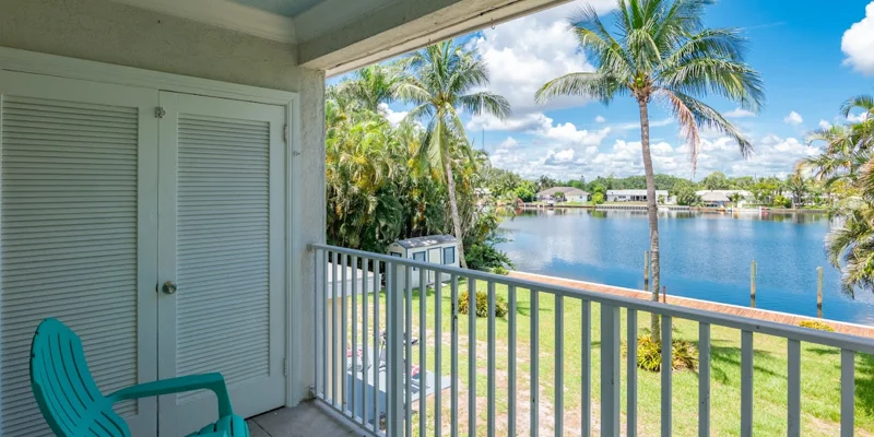 Balcony with chairs and lake view framed by palm trees