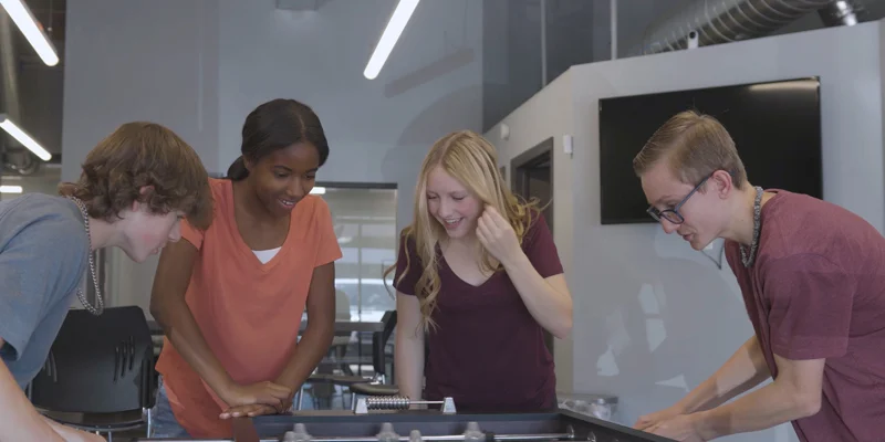 Group of young adults playing foosball.]