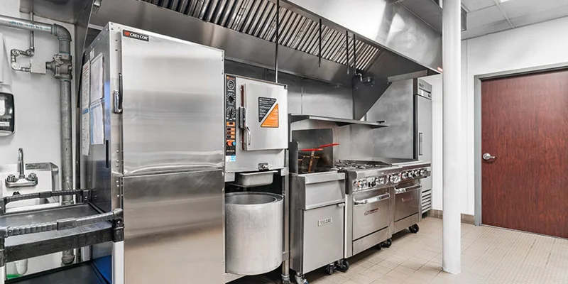 Industrial-style kitchen with ovens, stovetops, and vent hood