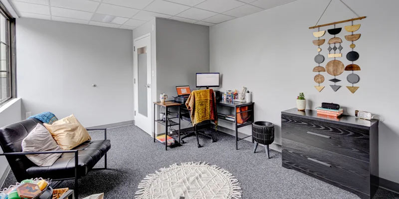 Therapy room with chairs, desk and decor.