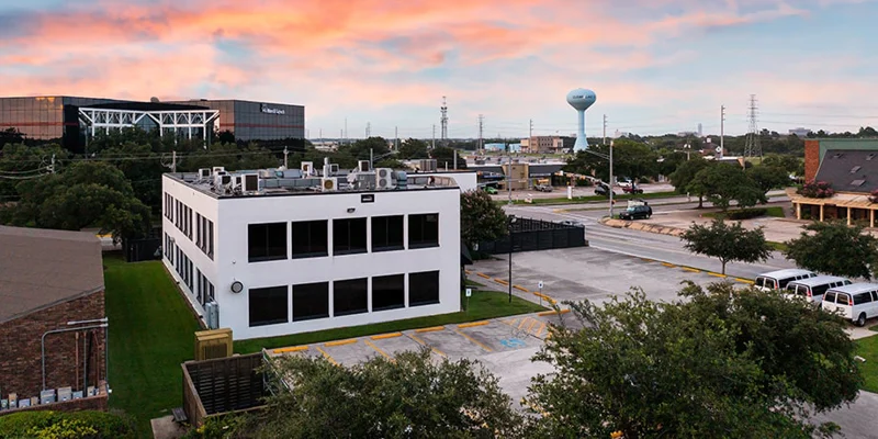 Side view of white rehab facility under a colorful sunset sky