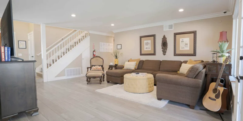 Lounge with couch, a TV, and a guitar, with a stairwell in view.