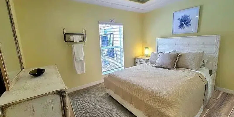 Private bedroom with a bed, dresser with a mirror, and a window.
