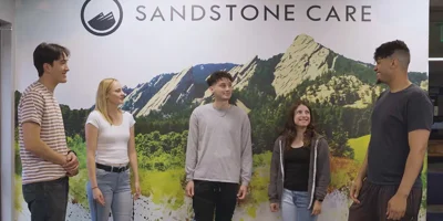 A group standing  in front of Sandstone Care backdrop.