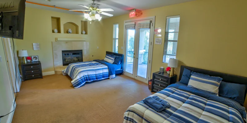 Shared bedroom with two beds, a fireplace, and a balcony.
