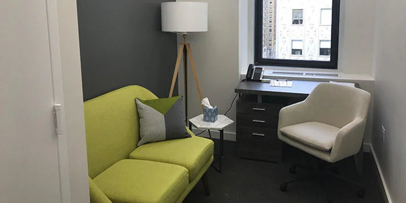 Therapy room with green sofa and desk.