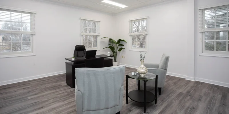 Therapy room with armchairs in front of an office desk.