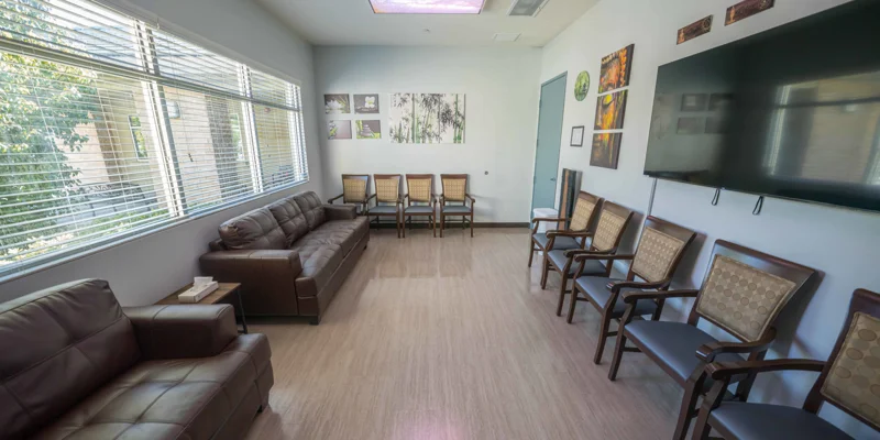 Group therapy room with chairs arranged for discussion, a TV and decor.