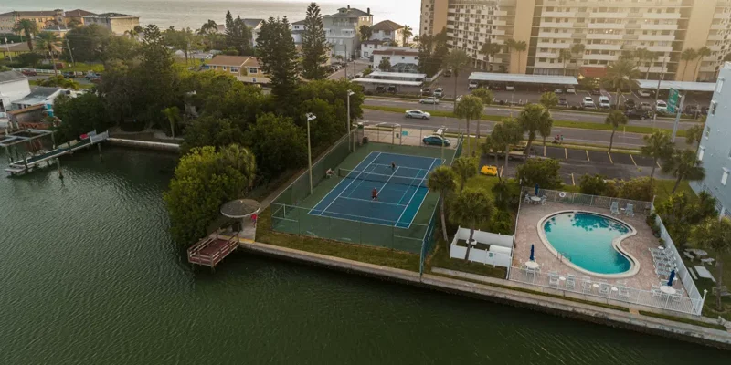 Aerial view of facility showing a tennis court, pool, and greenery.