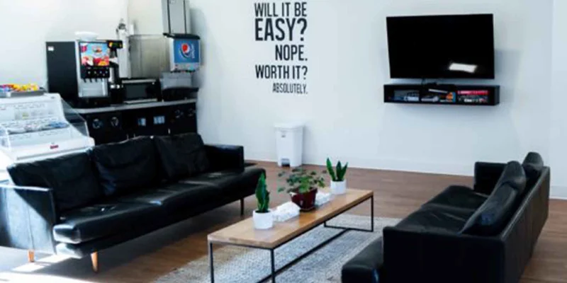A lounge with black couches, a TV, and a snack bar
