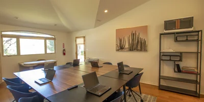 A meeting room with a long table, laptops, and a minimalist setup.