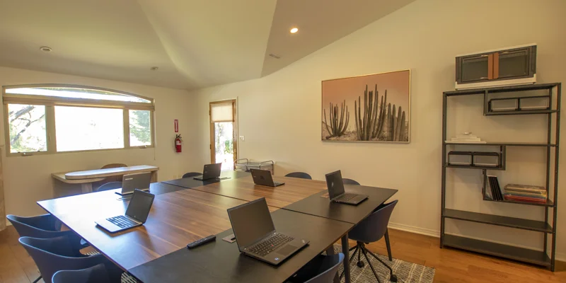A meeting room with a long table, laptops, and a minimalist setup.
