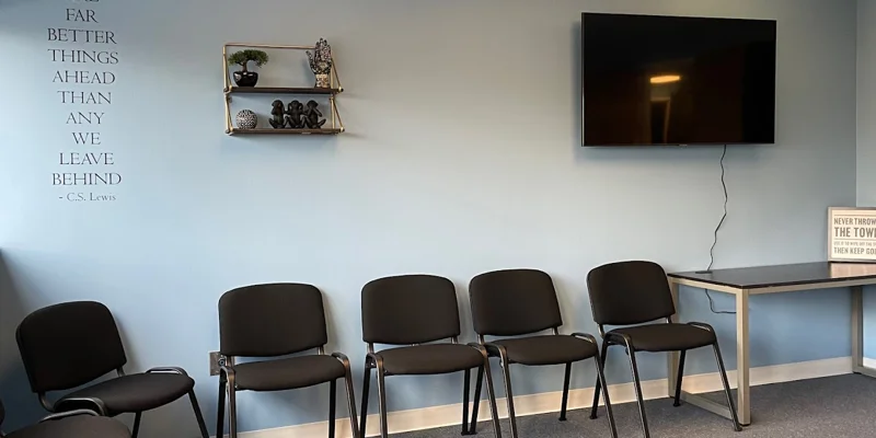 Group therapy room with black chairs and blue walls.