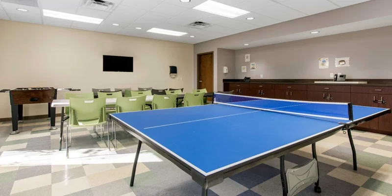 A recreational room featuring a ping-pong table, foosball, and seating.