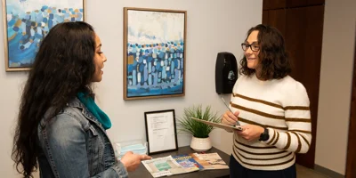 Two people talking near brochures in a lobby.