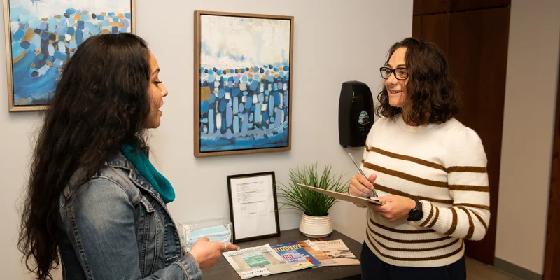 Two people talking near brochures in a lobby.