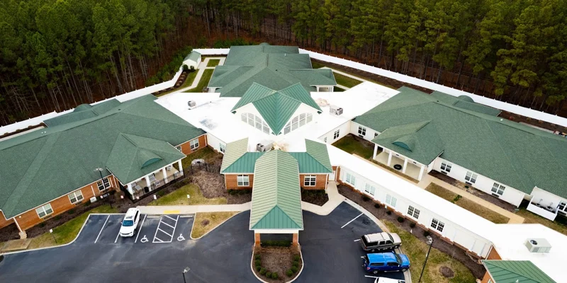 Aerial view of a rehab facility with green roofs and surrounding trees.