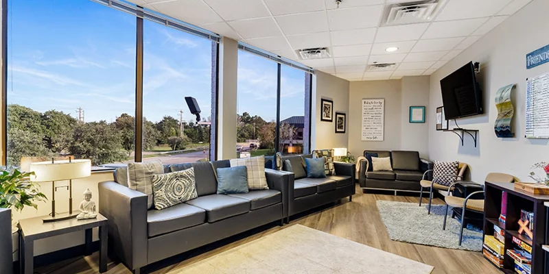Bright lounge area with black couches, TV, and board games