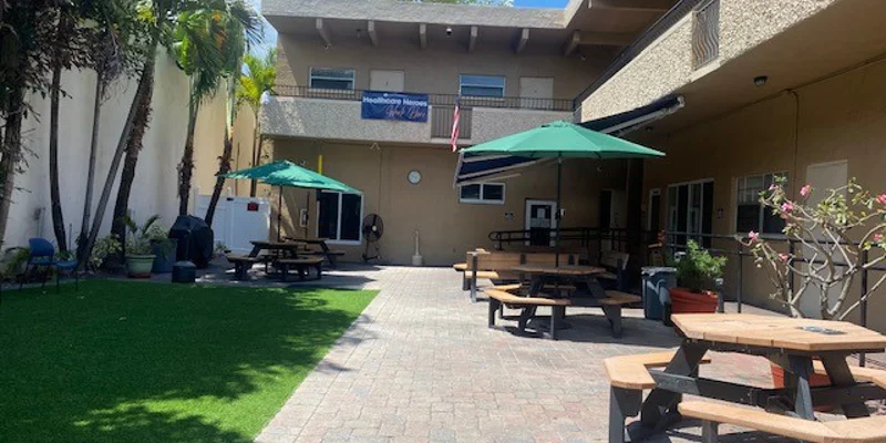 Outdoor courtyard with picnic tables, umbrellas, and greenery.