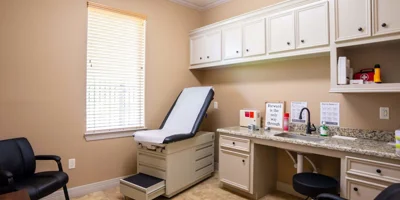 A clean medical exam room with a treatment bed and counter.