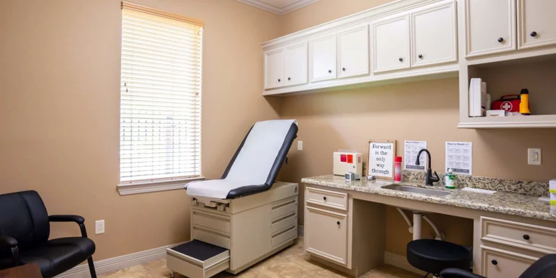 A clean medical exam room with a treatment bed and counter.