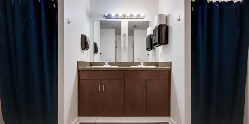 Bathroom with double sinks, dark wood cabinets, and shower curtains.
