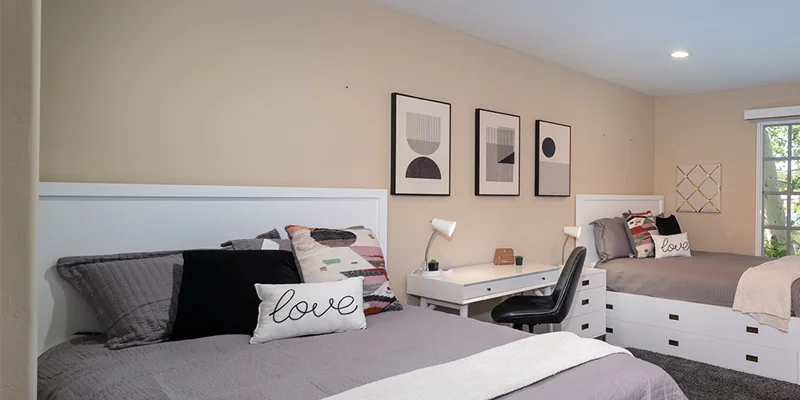 Shared bedroom with two beds and a desk.