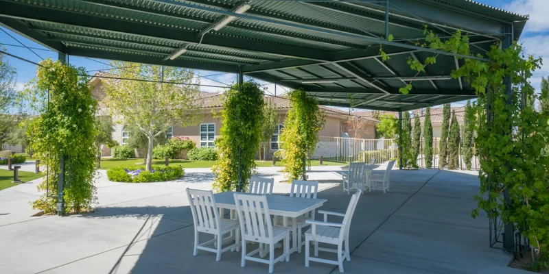 Outdoor seating area with greenery and a covered patio.