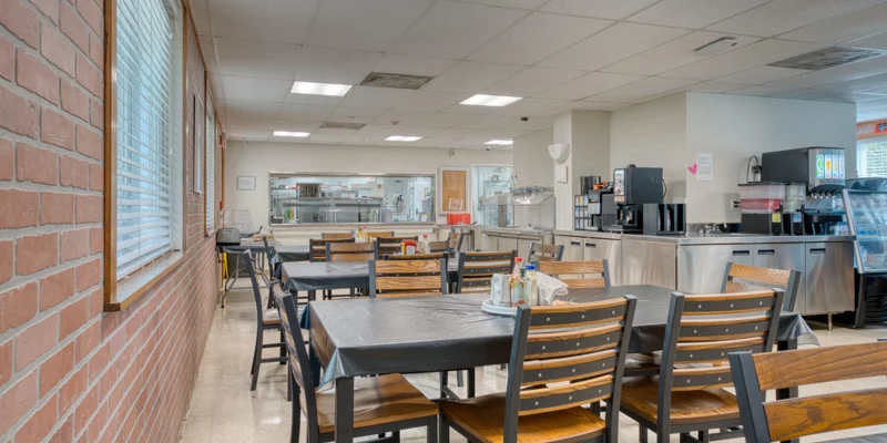 Cafeteria with dining tables, drink machines, and serving area.