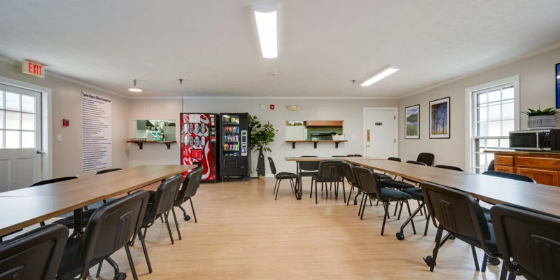 Meeting room with long tables, vending machines, and bright lighting.