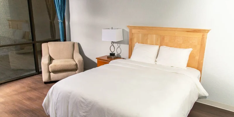 Private bedroom with a bed and and armchair.