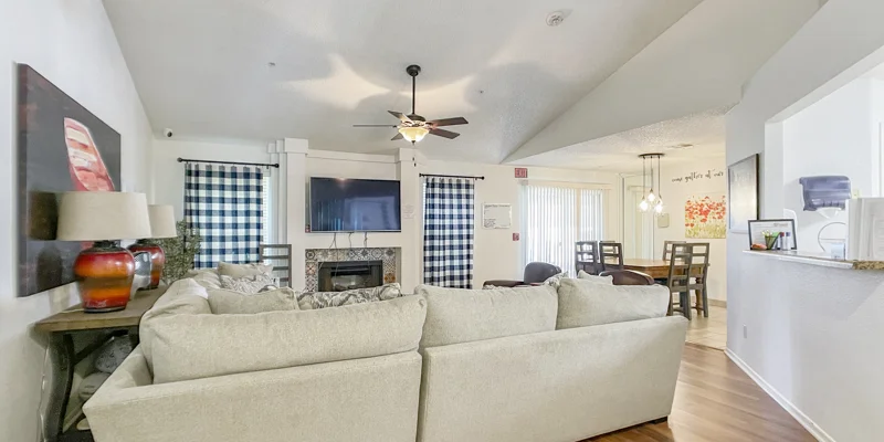 Living room with beige couches facing a fireplace and TV.