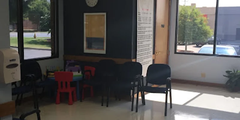 A  waiting area with chairs, windows, and a children's play area. 