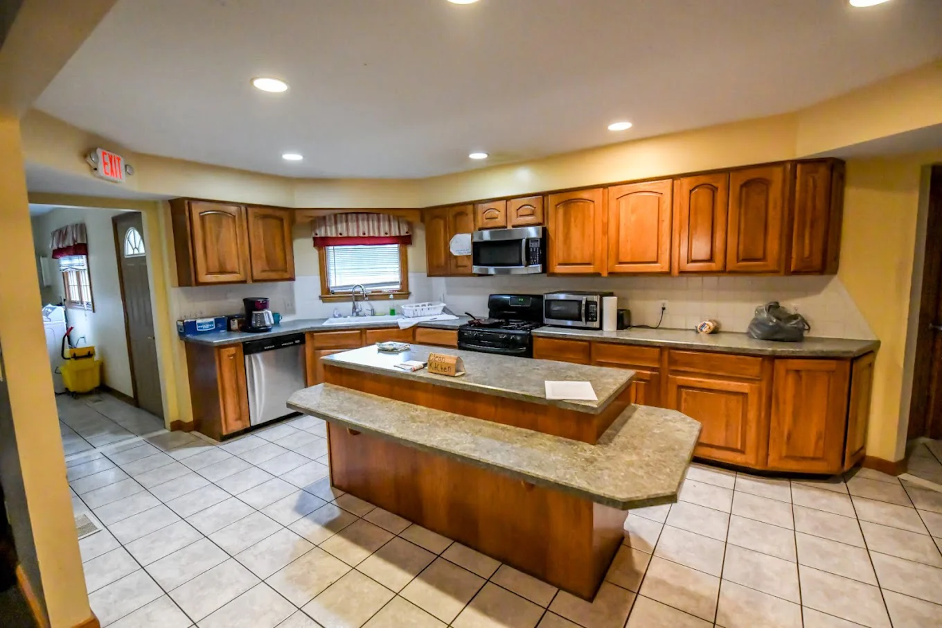 Bright kitchen with wooden cabinets, tiled flooring, and appliances.