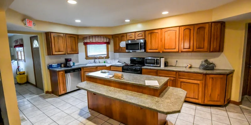 Bright kitchen with wooden cabinets, tiled flooring, and appliances.