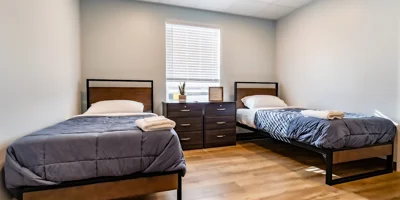 Two twin beds, striped bedding, nightstands, and wall tapestry.