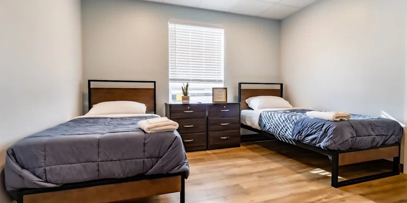 Two twin beds, striped bedding, nightstands, and wall tapestry.