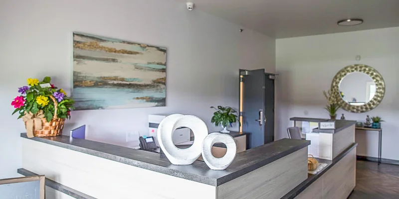 A reception area with a modern desk, artwork, and decorative items.