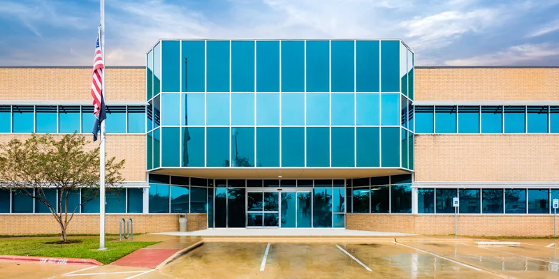 A modern rehab facility exterior with large glass windows and brick walls.