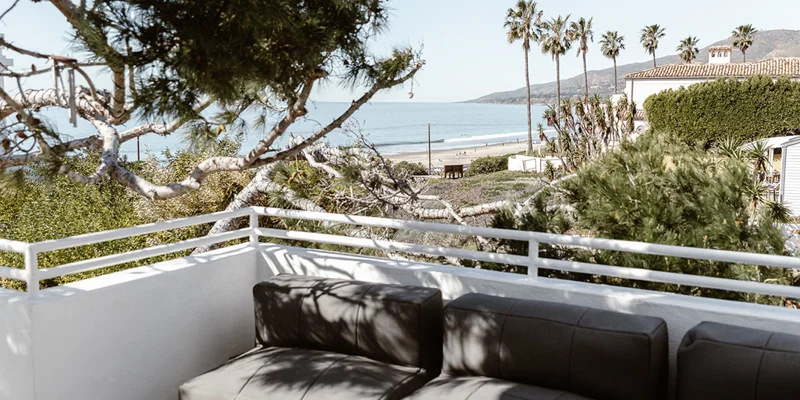 Rooftop seating area with ocean and palm tree views.