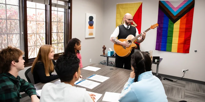 Recreational room with chairs at a table and a guitar.
