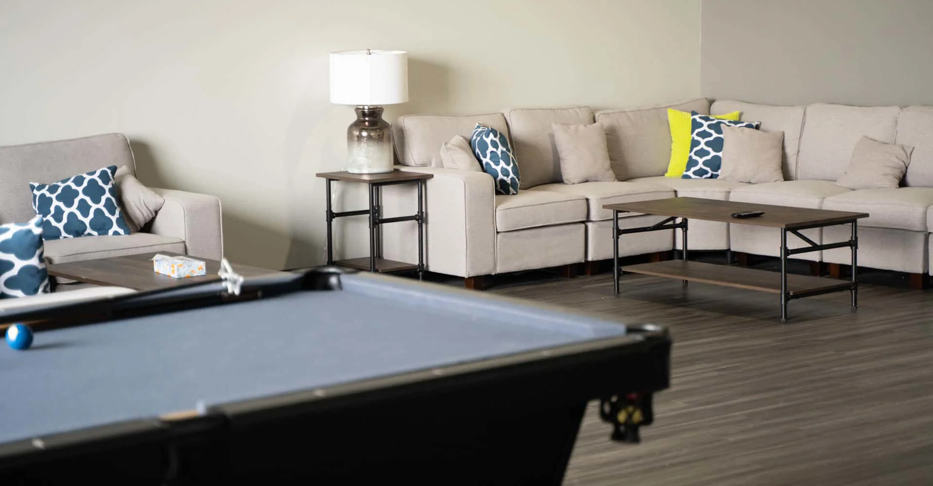 A cozy beige sectional couch with blue and yellow pillows in a lounge area.