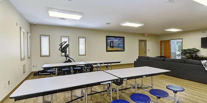 Common room with foldable tables, couch, and large wall TV.